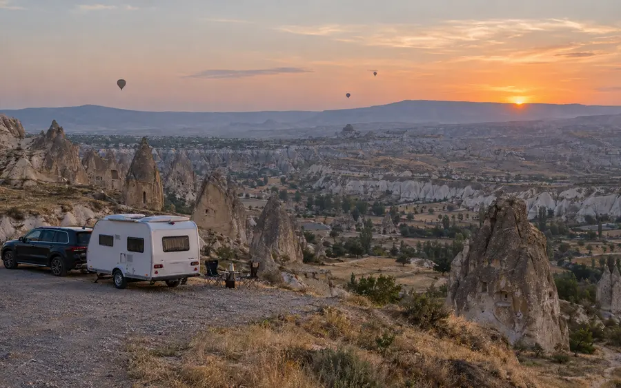 Kapadokya manzarasında gün batımında kamp yapan karavan